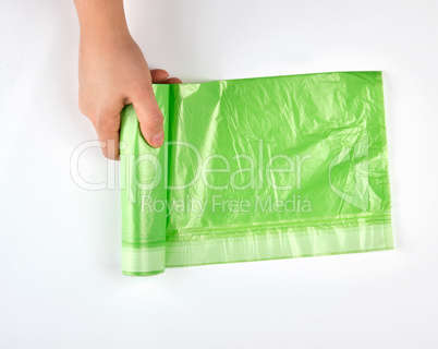 female hand unwind green roll with plastic bags for garbage