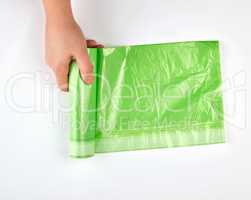 female hand unwind green roll with plastic bags for garbage