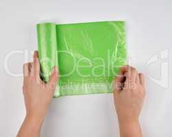 female hands unwinding a roll with polyethylene bags for garbage