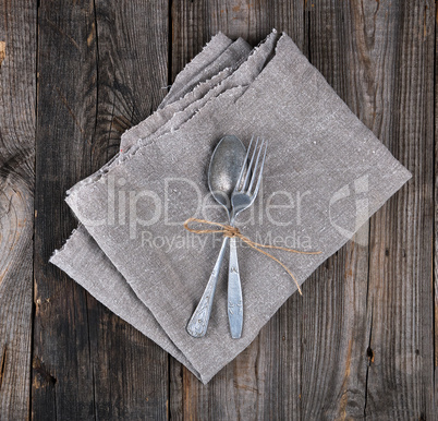 old metal fork and spoon tied with a brown rope on a gray linen