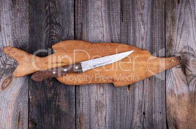 old wooden board in the form of a fish figure and a knife