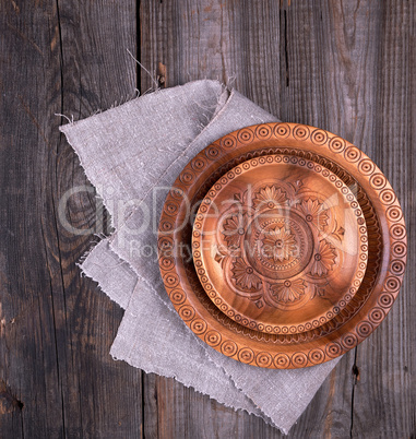 empty round brown carved decorative plate standing on a gray lin