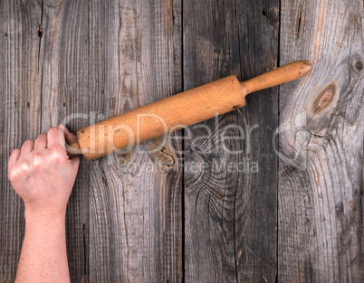 female hands hold old wooden rolling pin