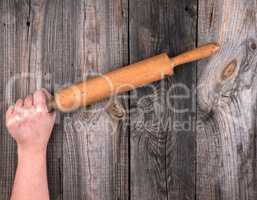 female hands hold old wooden rolling pin
