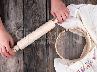 women's hands are holding an old wooden rolling pin on a gray ta