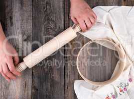 women's hands are holding an old wooden rolling pin on a gray ta