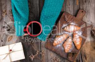 women's hands in a green knitted sweater holding a red ceramic m