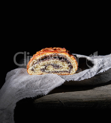 baked roll with poppy seeds on gray linen napkin