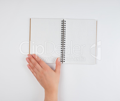 empty open notebook in a cell and a female hand