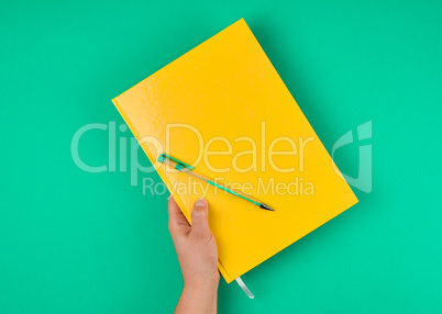 hand holds large closed yellow notebook