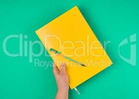 hand holds large closed yellow notebook