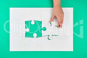 hand holds the missing element in the game of puzzles on a green