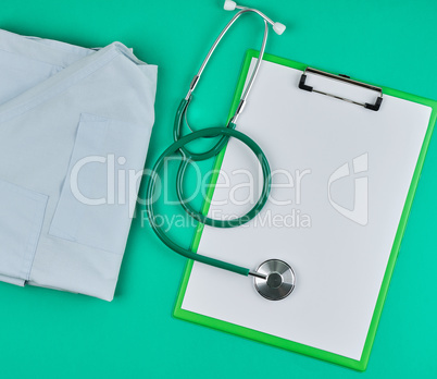 empty white sheets and a medical stethoscope on a green backgrou