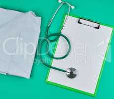 empty white sheets and a medical stethoscope on a green backgrou