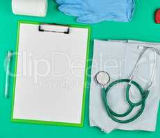 paper holder with empty white sheets, medical stethoscope, pills