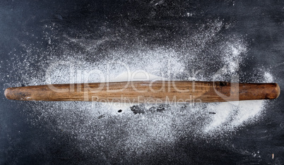 wooden rolling pin on a black background, top view