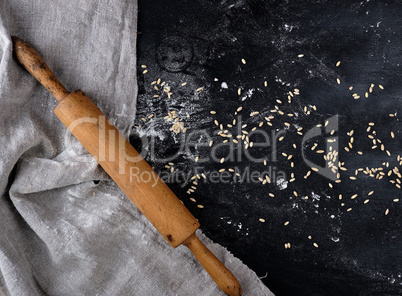wooden rolling pin on a black background, near a gray linen tow