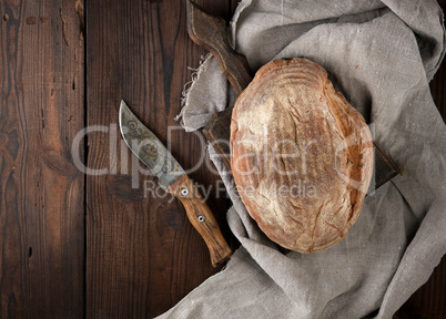 baked oval rye bread on a wooden cutting board