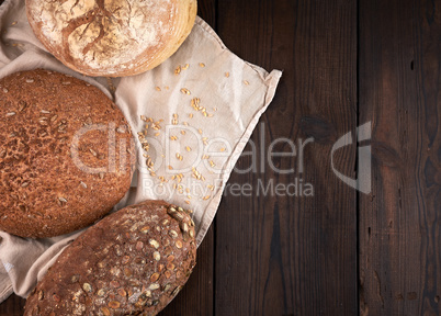 baked various breads on a beige kitchen towel, wooden background