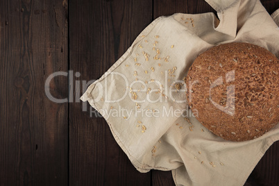 baked round rye bread with sunflower seeds on a beige textile na