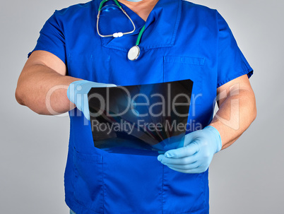 doctor in blue uniform and sterile latex gloves holds and examin
