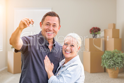 Happy Couple With New House Keys Inside Empty Room with Boxes