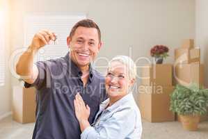 Happy Couple With New House Keys Inside Empty Room with Boxes