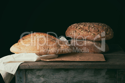 three baked loaves of bread on a wooden table,