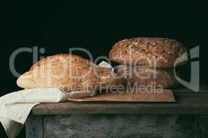 three baked loaves of bread on a wooden table,