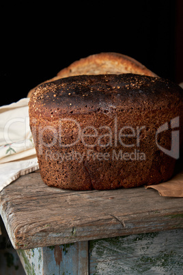 whole baked rye bread lying on a wooden table