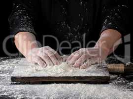 cook in a black uniform put two hands on a table