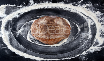 baked bread and white wheat flour scattered on a black table
