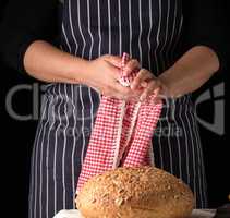 woman in a blue striped apron wipes her hands with a red textile