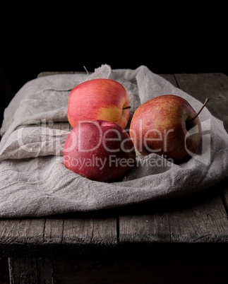 three fresh red apples lay on gray linen napkin