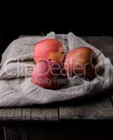 three fresh red apples lay on gray linen napkin