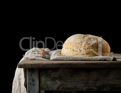 baked round white wheat bread on a textile towel, wooden old tab