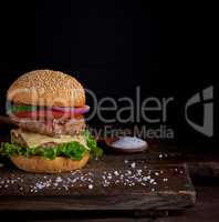 cheeseburger in a bun with sesame seeds, in the middle fresh veg