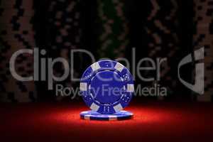 Closeup of blue poker chip on red felt card table surface with spot light on chip