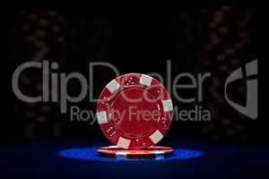 Closeup of red poker chip on blue felt card table surface with spot light on chip