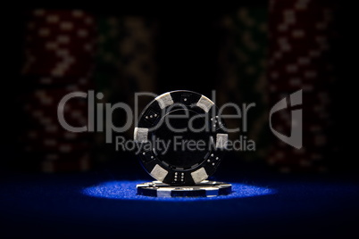 Closeup of poker chips on blue felt card table surface with spot light on chip