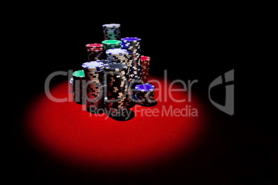 Stack of Poker chips on a red gaming poker table at the casino.