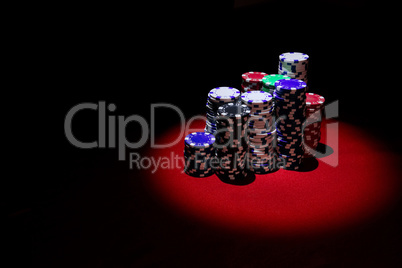 Stack of Poker chips on a red gaming poker table at the casino.