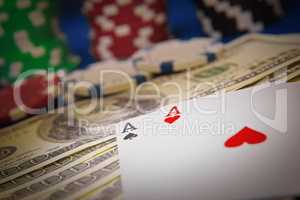 Close up of playing cards, poker chips and money.
