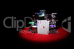Two aces with poker chips stack on red casino table