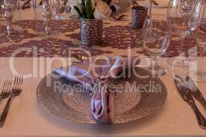 Purple place setting with a lilac colored napkin, white roses