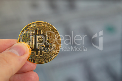 Male hand holding bitcoin, dollar background,macro shot