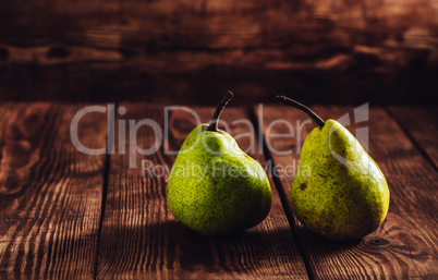 Two green pears on wooden background