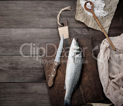 fresh whole sea bass fish on brown cutting board