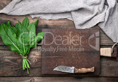bunch of fresh green sorrel leaves and old brown cutting board