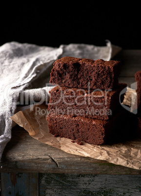 A stack of baked square pieces of chocolate brownie cake on brow